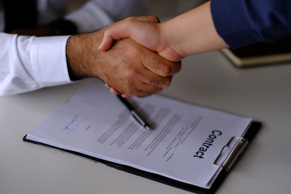Business partners signing a contract by hand during a deal negotiation