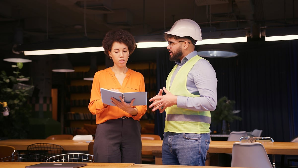 Project manager discussing building plans with an engineer, concluding their meeting with a handshake